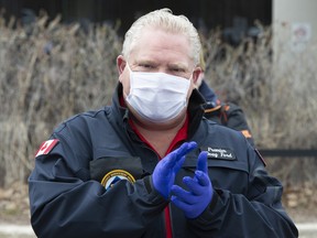 Ontario Premier Doug Ford applauds as he hands out prepared meals to front line health care workers at Scarborough Health Network hospital in Toronto on Friday April 24, 2020.