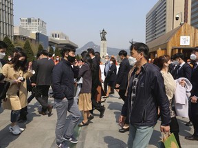 People wearing face masks to help protect against the spread of the new coronavirus walk across a pedestrian crosswalk in Seoul, South Korea, Thursday, April 2, 2020. Increasingly frustrated health officials say they are prepared to take more aggressive measures to track and contain people with COVID-19 as the number of sick and dead continues to soar.