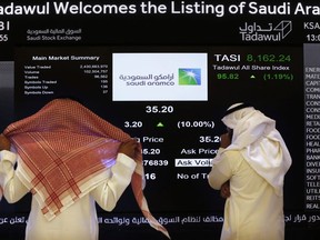 Saudi stock market officials watch the stock market screen displaying Saudi Arabia's state-owned oil company Aramco after the debut of Aramco's initial public offering (IPO) on the Riyadh's stock market in Riyadh, Saudi Arabia, Wednesday, Dec. 11, 2019. A global pandemic and a parallel crash in oil prices helped push lobbying in Ottawa to record heights over the last two months.