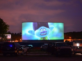 people watch the movie Trolls from their cars, separated from other cars by a 10-foot orange fencing in an effort to respect social distancing amid the novel coronavirus pandemic, at the Ocala drive-in theatre in Ocala, Florida