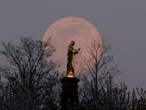 The pink supermoon rises behind the Sacre-Coeur du Horn statue depicting the Christ figure during Holly Week in Wolxheim, near Strasbourg, France April 7, 2020.