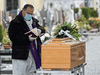 A priest wearing a face mask checks a book of funeral rites as he gives the last blessing to a deceased person during a funeral ceremony in Bolgare, Lombardy.