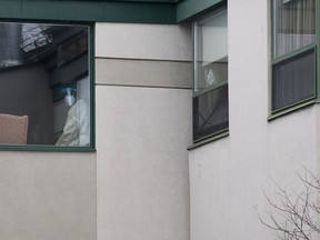 A healthcare worker looks out of a window at Maison Herron, a long term care home in the Montreal suburb of Dorval, Que., on Saturday, April 11, 2020, as COVID-19 cases rise in Canada and around the world.