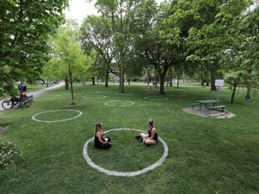 Women sit in a field where circles were painted to help visitors maintain social distancing to slow the spread of COVID-19 at Trinity Bellwoods park in Toronto, Ontario, May 28, 2020.