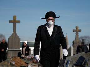 A member of the Charitable Brotherhood of Saint-Eloi de Bethune, which first formed during the plague 800 years ago, wears a protective face mask as he walks through a cemetery during a burial ceremony in Bethune, France, on March 18.