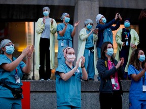 Healthcare workers applaud and film with their phones as Toronto first responders parade down hospital row in Toronto, Ontario, Canada, in a salute to healthcare workers on April 19, 2020, amid the novel coronavirus pandemic.