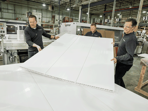 Trusscore executive vice-president Joel Koops, from left, president Steve Bosman and CEO Dave Caputo move one of their temporary plastic walls that are being created to be put up at hospitals to stop the spread of COVID-19.