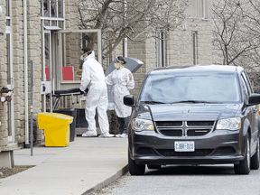 Pushing an empty stretcher, a man enters Anson Place Care Centre in Hagersville, Ont., to remove a body from the long term care and retirement home, April 12, 2020.