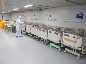 This photo taken on April 14, 2020 shows a staff member spraying disinfectant on empty beds after all patients left Leishenshan Hospital in Wuhan in China's central Hubei province.