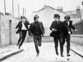 From left to right, Paul McCartney, George Harrison, John Lennon, and Ringo Starr run down an empty London street in a scene from the movie A Hard Day's Night.