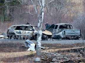 An RCMP investigator inspects vehicles destroyed by fire at the residence of Alanna Jenkins and Sean McLean, both corrections officers, in Wentworth Centre, N.S. on Monday, April 20, 2020.