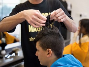 A hairdresser cuts a teenage boy's head at his salon in the central Israeli city of Rehovot on  February, 2015. Hairdressers in Israel are gradually opening as lockdown measures are eased.