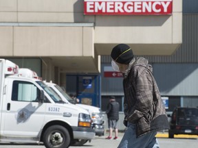 A man wears a protective face mask as he walks past the emergency department of the Royal Columbian Hospital in New Westminster, B.C. Friday, April 3, 2020. Health-care providers are warning of an unseen toll COVID-19 could take if people die because they are too afraid to go to an emergency room for serious health issues unrelated to the pandemic.