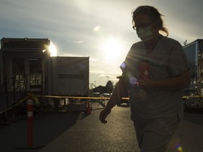 A health-care worker is silhouetted as they walk past the British Columbia mobile medical unit set up outside of Abbotsford Regional Hospital in Abbotsford, B.C. Tuesday, April 14, 2020. The mobile medical unit was deployed to Abbotsford to assist with the COVID-19 outbreak that has occurred at the Mission Correctional Institution.