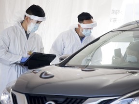 A Fraser Health healthcare worker speaks to a patient at a drive through COVID-19 testing facility in Burnaby, B.C., Monday, April 6, 2020.