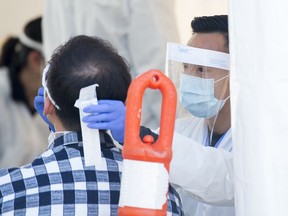 A Fraser Health healthcare worker tests a patient at a drive through COVID-19 testing facility in Burnaby, B.C., Monday, April 6, 2020.