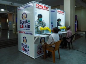 Medical staff collect samples from people at newly set upped Walk-In Sample Kiosk (WISK) to test for the COVID 19 coronavirus at Ernakulam Medical College in Kerala on April 6, 2020.