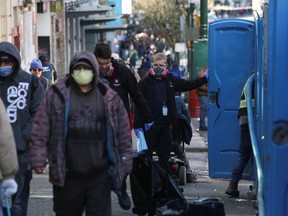 Contractors wearing protective masks clean a series of portable toilets installed along Hastings Street in Vancouver's Downtown Eastside, as the number of coronavirus disease (COVID-19) cases continues to grow in Vancouver, British Columbia, Canada March 25, 2020.
