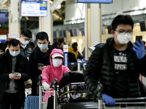 Travelers wearing protective masks wait in line in the international departures area in Vancouver International Aiport (YVR) in Vancouver, British Columbia, Canada, on Tuesday, March 17, 2020. Prime Minister Justin Trudeau's government is significantly restricting the entry of non-residents into Canada to combat the spread of the coronavirus.