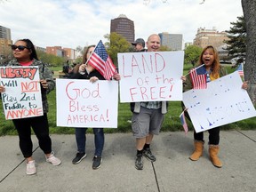 Protesters hold signs encouraging people to demand that businesses be allowed to open up, and people allowed to go back to work, at the Country Club Plaza on April 20, 2020 in Kansas City, Missouri.