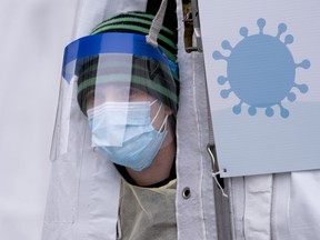 A health-care worker peers from a tent at a walk-in COVID-19 test clinic in Montreal on Monday, March 23, 2020.