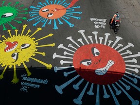 A motorcyclist rides past a mural of the COVID-19 coronavirus in Chennai, India, on April 13, 2020.