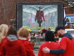 Mourners, asked to wear red are seen near a mural dedicated to slain RCMP Const. Heidi Stevenson, during a province-wide, two-minutes of silence for the 22 victims of last weekend's shooting rampage, in front of the RCMP detachment in Cole Harbour, N.S., Friday, April 24, 2020.