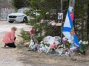 A woman pays her respects to mass shooting victims at a roadblock in Portapique, N.S. on April 22, 2021.
