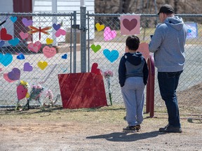 A man and his son pay respects at a memorial to Lisa McCully, a teacher at Debert Elementary School in Debert, N.S., on April 21.