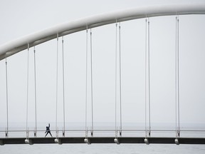 A lone person stretches overlooking Lake Ontario on the Humber Bay bridge in Toronto on Monday, April 13, 2020. Health officials and the government have asked that people stay inside to help curb the spread of COVID-19.