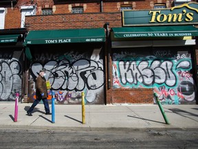 A lone person walks past closed businesses in Toronto's Kensington Market on April 15, 2020.