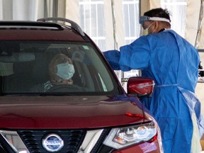 A frontline healthcare worker attends people at the Etobicoke General Hospital drive-thru COVID-19 assessment centre as the number of coronavirus disease  cases continue to grow, in Toronto on April 9, 2020.