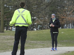 A bylaw enforcement officer talks to a woman in a park in Toronto on April 5.