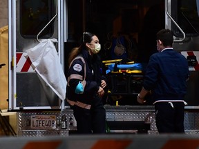 Paramedics wearing facemasks work behind an ambulance at the Garfield Medical Center in Monterey Park, California on March 19, 2020.