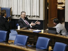 Manitoba premier Brian Pallister, centre, speaks with Ministers Ron Schuler, left, and Jeff Wharton at an emergency COVID-19 physically distanced session at the Manitoba Legislature in Winnipeg, Wednesday, April 15, 2020. Manitoba drivers are going to get insurance rebates in the coming weeks. The provincial government says it's planning to issue cheques with rebates of 11 per cent, worth roughly $150 for the average policy holder.THE CANADIAN PRESS/John Woods