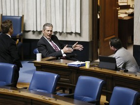 Manitoba premier Brian Pallister, centre, speaks with Ministers Ron Schuler, left, and Jeff Wharton at an emergency COVID-19 physically distanced session at the Manitoba Legislature in Winnipeg, Wednesday, April 15, 2020.