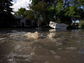 Water bubbles out of a manhole along a street near the Elbow River during flooding in Calgary, Alta., Saturday, June 22, 2013. A First Nation says it is ending its opposition to a proposed flood-diverting reservoir west of Calgary because it negotiated a $32-million grant from the province.