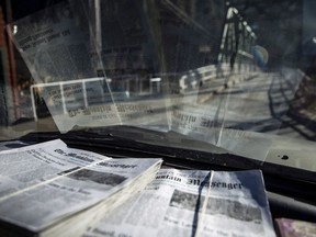 In this Dec. 13, 2018, photo, copies of the new issue of the Mountain Messenger sit on Scott McDermid's dashboard as he drives to stock newspaper boxes at the Courthouse and Sheriff's office in Downieville, Calif.