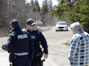 RCMP officers speak with a man in Portapique, Nova Scotia, after search for a mass shooting suspect ended on April 19, 2020.
