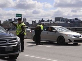 Quebec police officers randomly stop traffic entering Quebec from Ottawa on Wednesday, April 1, 2020, during the COVID-19 pandemic.