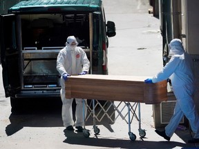 Mortuary workers push a coffin of a person who died at a nursing home during the coronavirus disease (COVID-19) outbreak in Leganes Madrid, near Madrid, Spain, April 2, 2020.