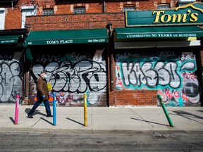 A lone person walks past closed businesses in Kensington Market in Toronto on Wednesday, April 15, 2020.