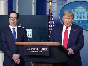 U.S. Secretary of the Treasury Steve Mnuchin listen to US President Donald Trump speak during the daily briefing on the novel coronavirus, which causes COVID-19, in the Brady Briefing Room at the White House on April 13, 2020, in Washington, DC