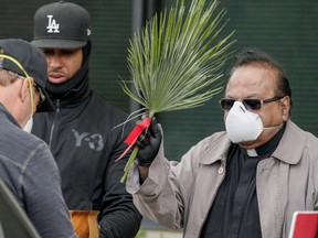 Associate Pastor Father Vivian Ben Lima gives a blessing to a congregant outside St. Mel Catholic Church on Palm Sunday during the outbreak of the coronavirus disease (COVID-19) in Woodland Hills, California, U.S., April 5, 2020.