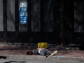 A man sleeps on a sidewalk in the Downtown Eastside of Vancouver, on Sunday, April 12, 2020. A local media outlet has reported two cases of COVID-19 have been confirmed at a homeless shelter in the Downtown Eastside.