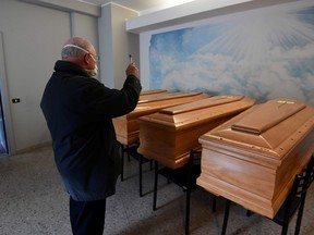Italian priest of the small town of Albino, Don Giuseppe Locattelli  blesses coffins of the deceased in a mortuary cell on March 25, 2020 in Albino, during the country's lockdown following the COVID-19 new coronavirus pandemic.
