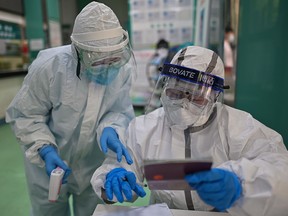 Medical workers check information as they process swab samples for testing for COVID-19 in Wuhan, China, on April 16, 2020.