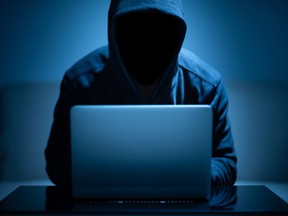 Hacker dark face using laptop in the dark room. Getty Images