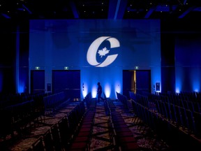 A man is silhouetted walking past a Conservative party logo before the opening of the party's national convention in Halifax in 2018.