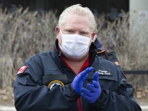 Ontario Premier Doug Ford applauds as he hands out prepared meals to front line health care workers at Scarborough Health Network hospital in Toronto on Friday, April 24, 2020.